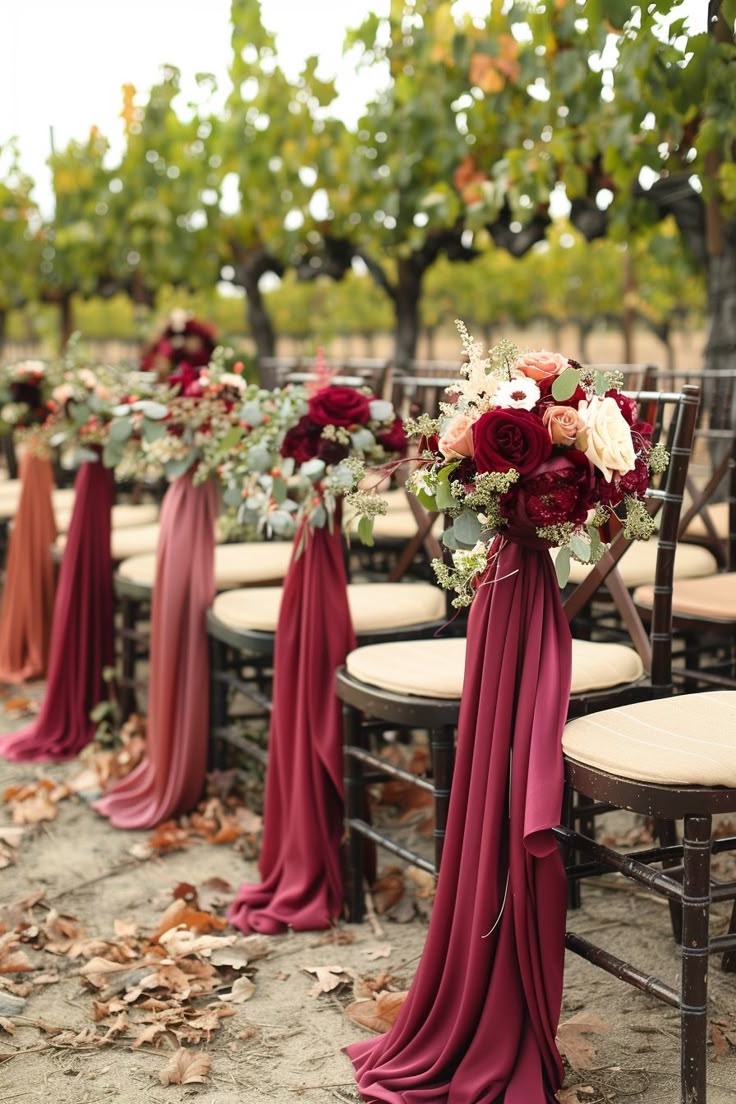 Ceremony chairs draped in burgundy fabric with rose bouquets