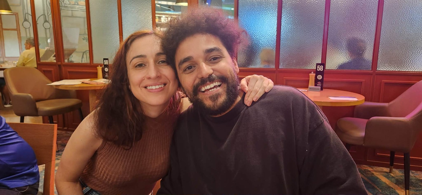 Vanessa and Clifton smiling cheek to cheek at a restaurant table
